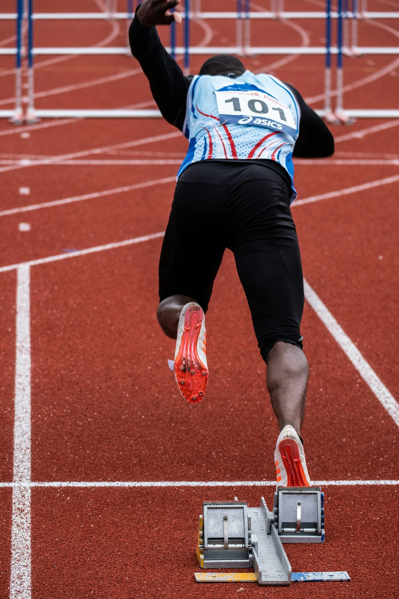 Terminer l’échauffement avec des accélérations progressives pour être prêt à performer. Un sprinter sur une piste s’élançant des starting blocks, illustrant l’importance des accélérations en fin d’échauffement.