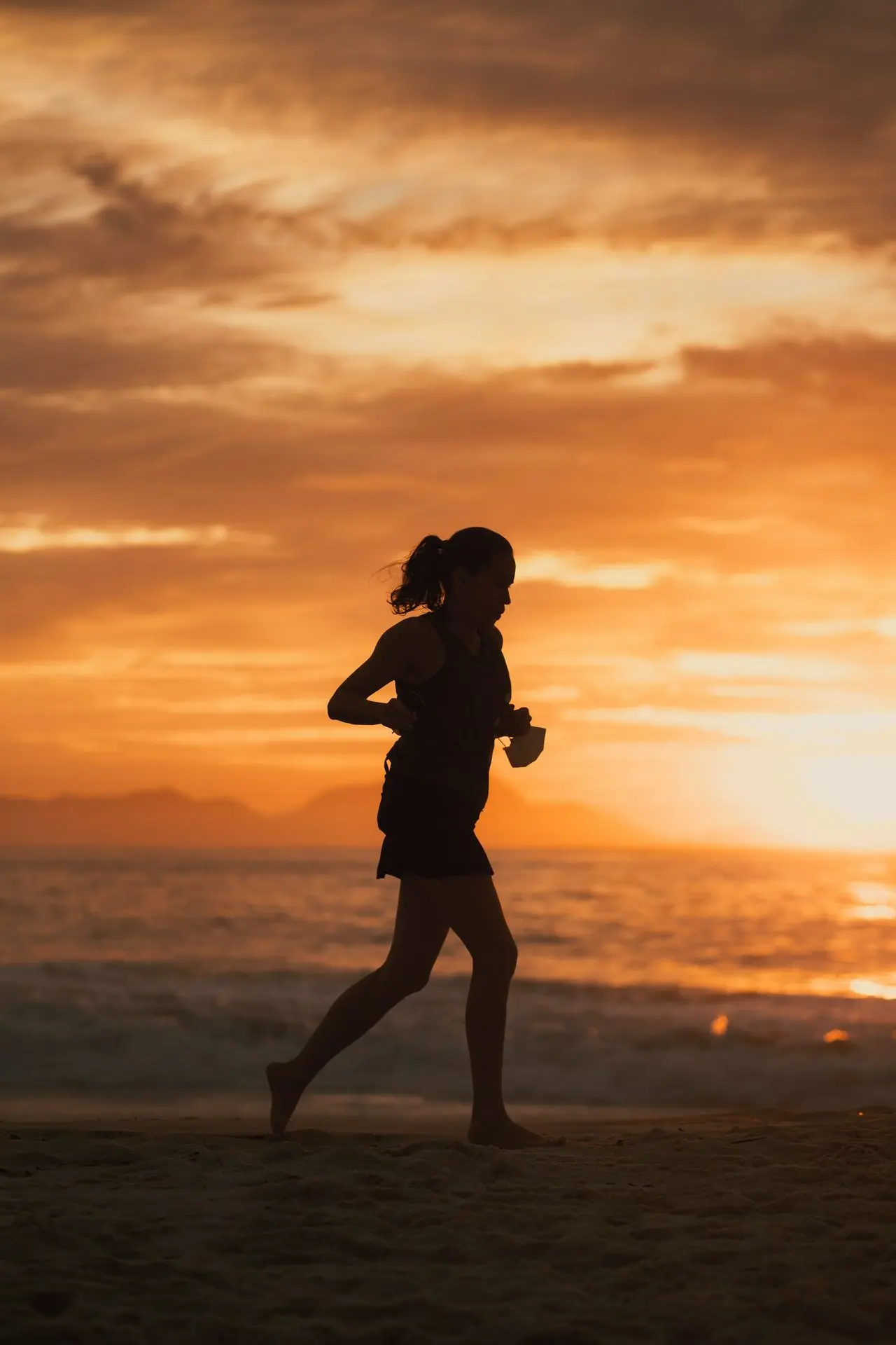 Un bon échauffement commence toujours en douceur. Une femme en plein footing sous un coucher de soleil magnifique, une ambiance parfaite pour préparer son corps à l’effort.