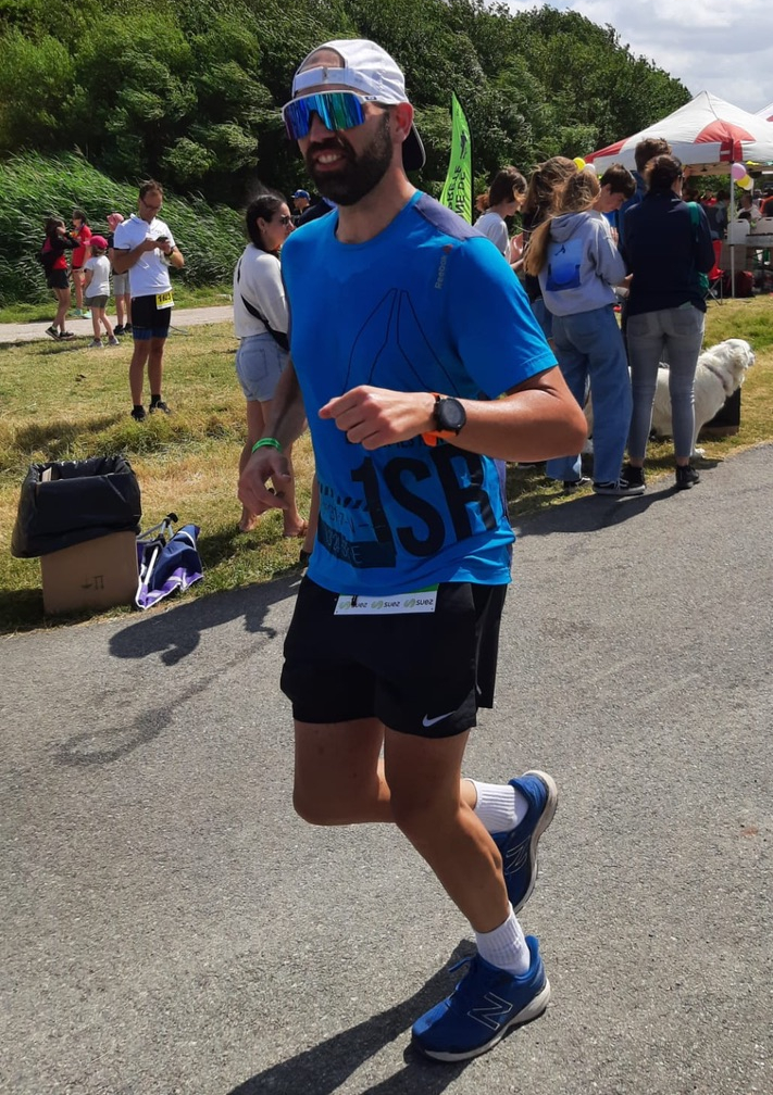 Sur le marathon du Full Ironman, portant un t-shirt bleu et une casquette blanche. Malgré la fatigue accumulée, le sourire est là, porté par l’adrénaline et l’ambiance incroyable.