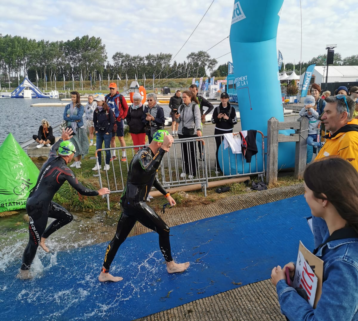 Premier soulagement après l’épreuve de natation. Passage sous l’arche avec le pouce levé, prêt pour la suite du défi. L’énergie est au rendez-vous.
