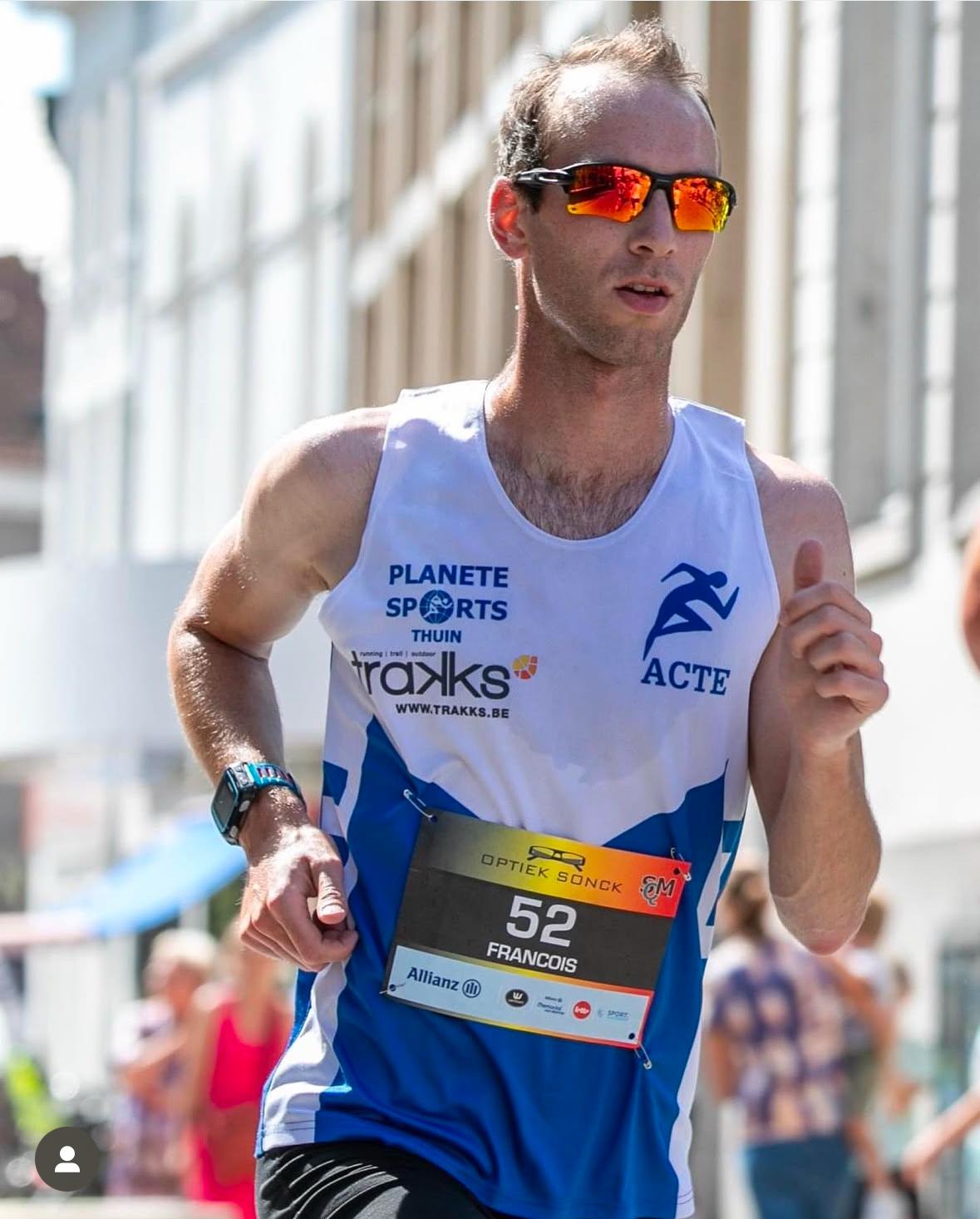 Un bon équipement, un atout pour progresser François, concentré sur sa course, portant un singlet sponsorisé par Trakks et des lunettes de soleil. Un bon équipement permet de rester focus et d’optimiser sa performance.