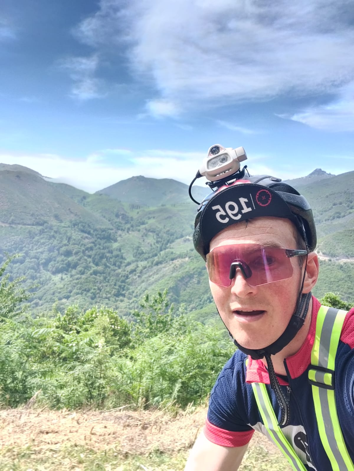 Fatigue visible mais émerveillement intact : Pierre capture un moment unique sur son vélo, avec un panorama grandiose en arrière-plan.