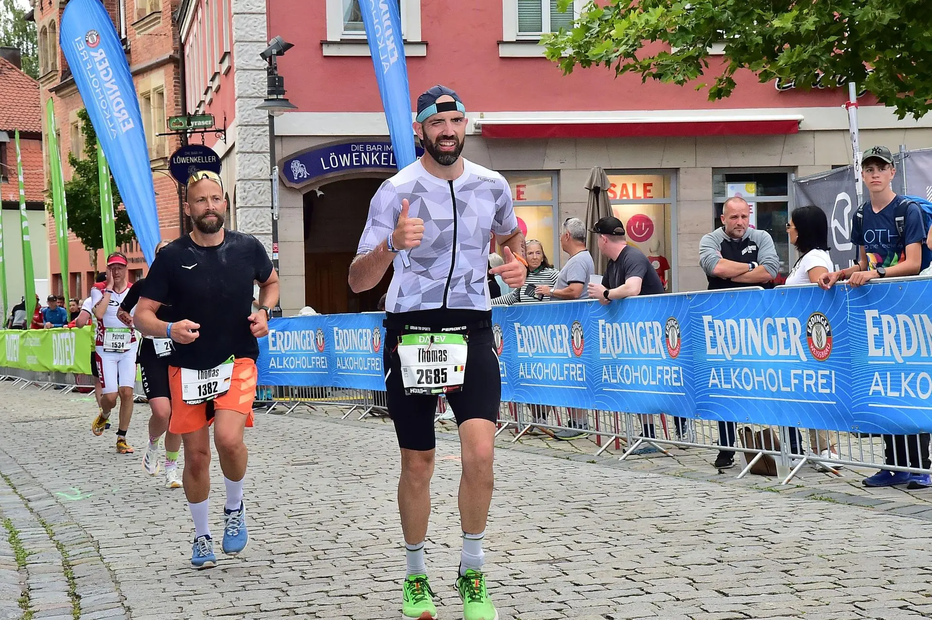 Sourire et confiance, le marathon commence bien ! En pleine course à pied, clin d’œil et pouce levé au photographe. L’énergie est encore là, la trifonction blanche Fusion toujours impeccable.