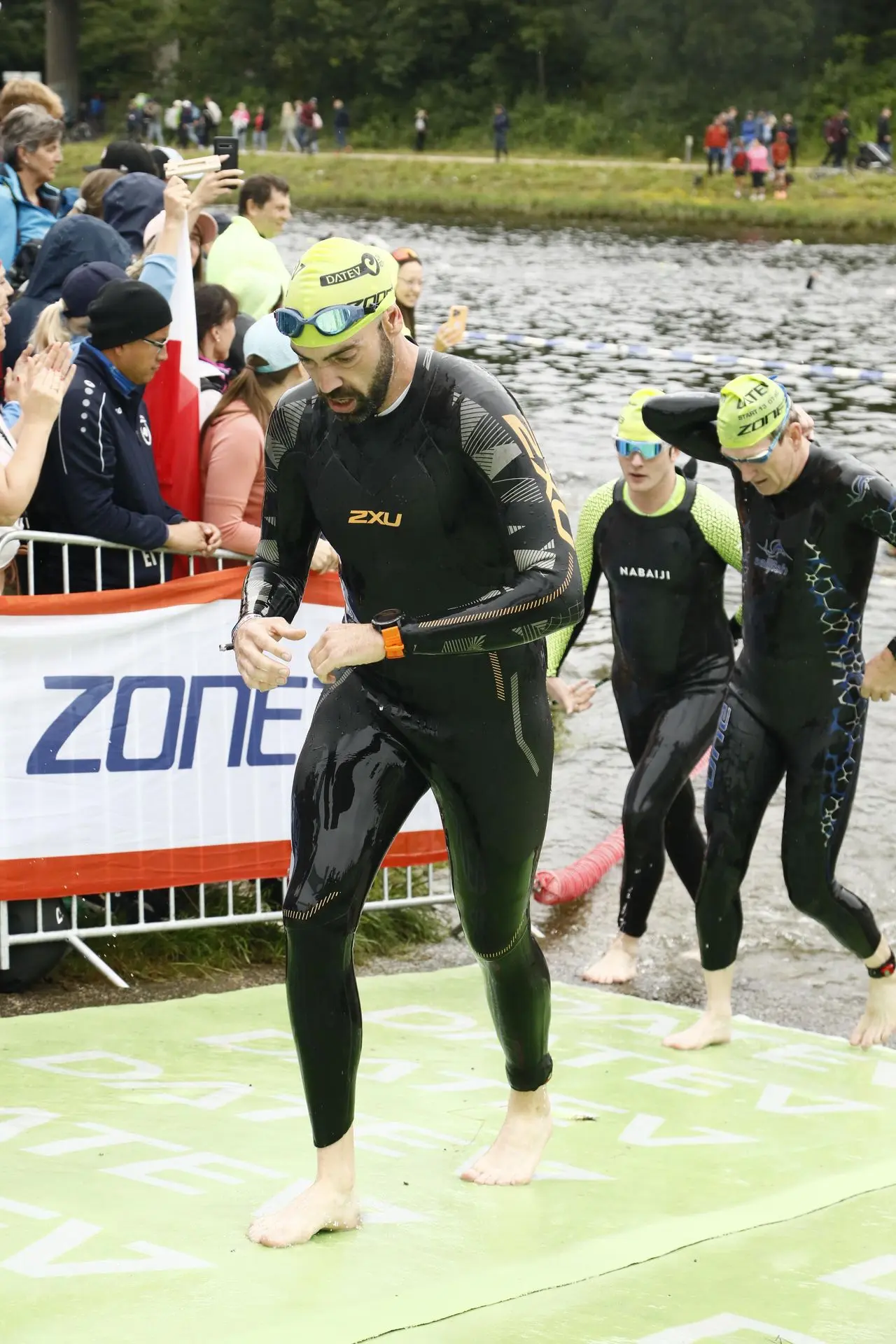 La natation validée, le chrono checké… en route pour le vélo ! Sortie de l’eau lors de mon second Full Ironman, combinaison noire encore ruisselante, bonnet vert bien en place. Mon regard se pose sur ma Garmin Fenix 5X Plus au bracelet orange, un instant pour vérifier mon temps. Un sentiment de satisfaction après une bonne nage, prêt à attaquer la suite !